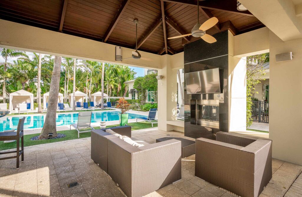 Covered grilling pavilion by the pool with sofas, TV, and fire place